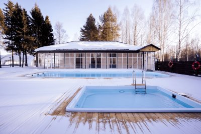 Композитные бассейны с голубой водой зимой, деревянный настил и панорамное здание
